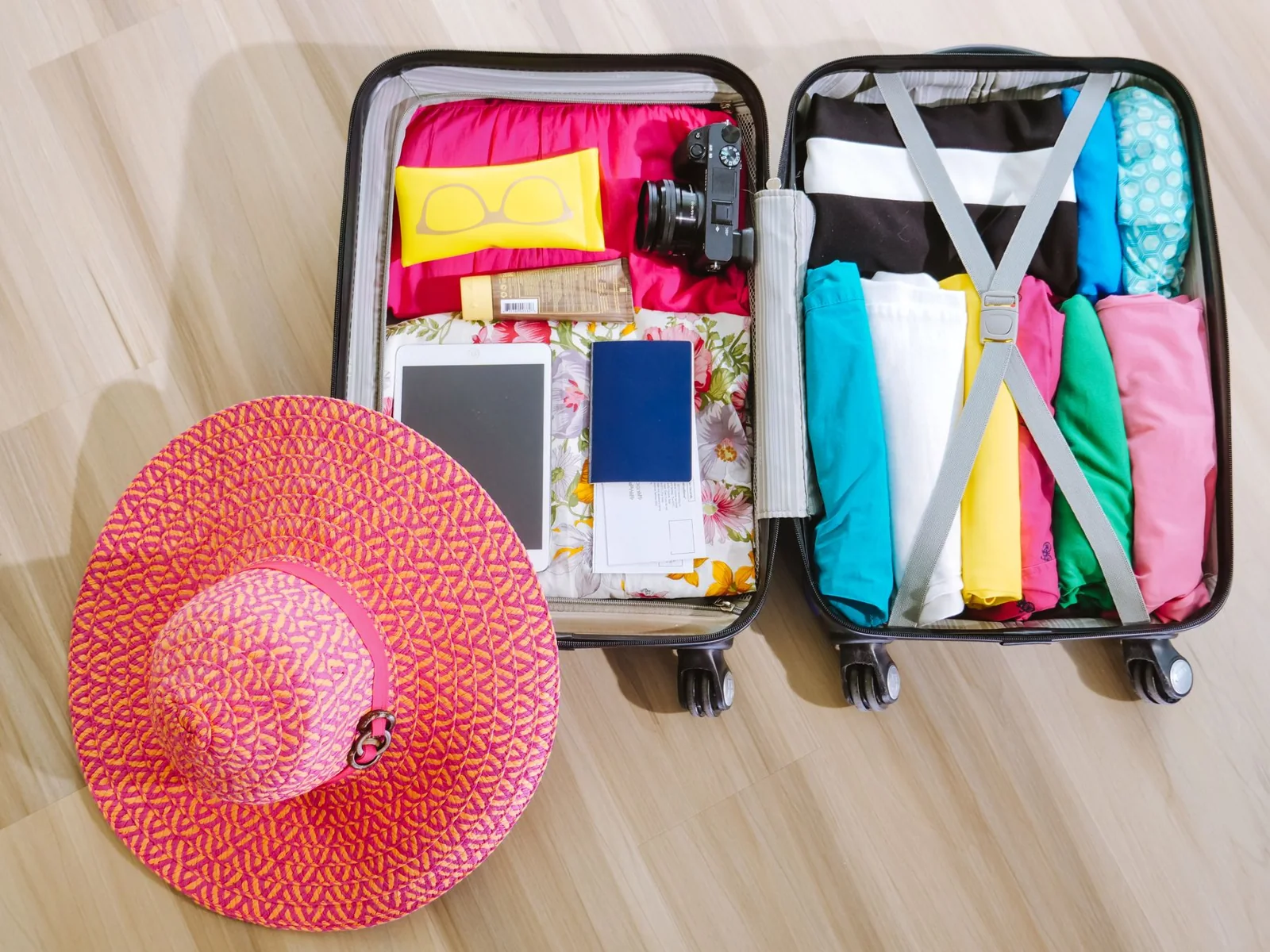 Valise ouverte avec vêtements pliés et accessoires de voyage, prête pour le départ