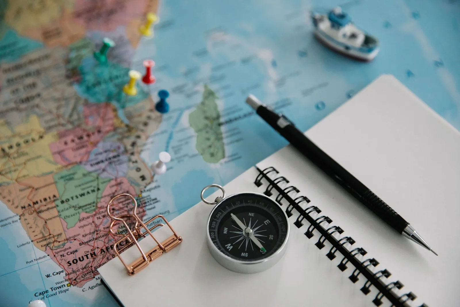 Carnet vierge, stylo et boussole disposés sur une carte pour préparer un voyage